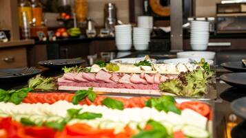 A buffet with various food items including meats, cheeses, and vegetables.