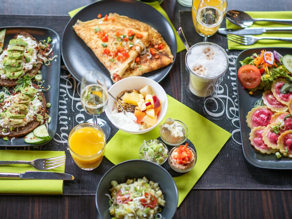 Variedad de platos sobre una mesa con posavasos, cubiertos y un vaso de zumo de naranja.