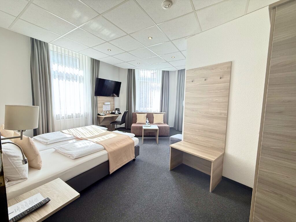 Une chambre d’hôtel équipée d’un lit, d’un bureau, d’une chaise, d’une télévision et d’un grand panneau en bois.