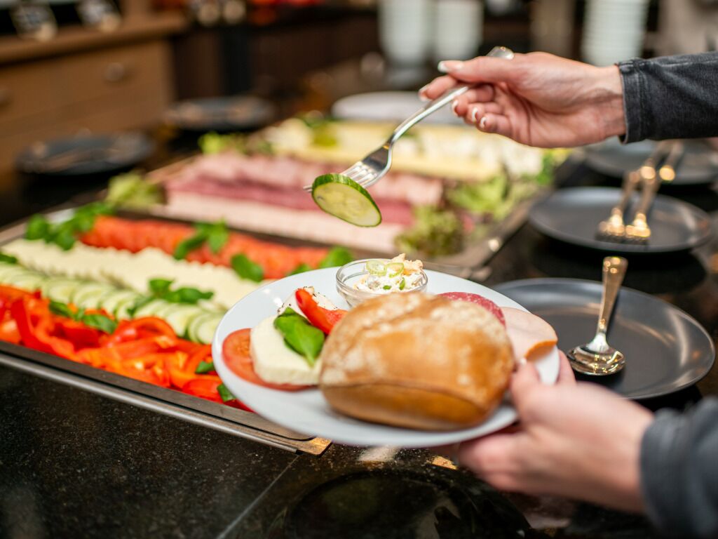 A buffet with various food items and a person serving themselves.