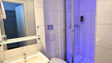 A modern bathroom with a white sink, toilet, and shower area.