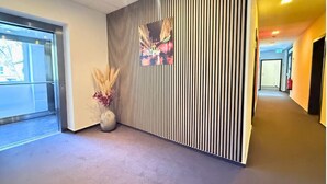 Un interior moderno con una pared a rayas, un jarrón con plantas secas y un pasillo que conduce a otra habitación.