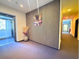 Ein modernes Interieur mit einer gestreiften Wand, einer Vase mit Trockenpflanzen und einem Gang zu einem weiteren Raum.