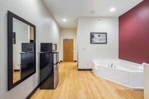 Une salle de bain moderne avec une baignoire, un miroir et une porte donnant sur une autre pièce.