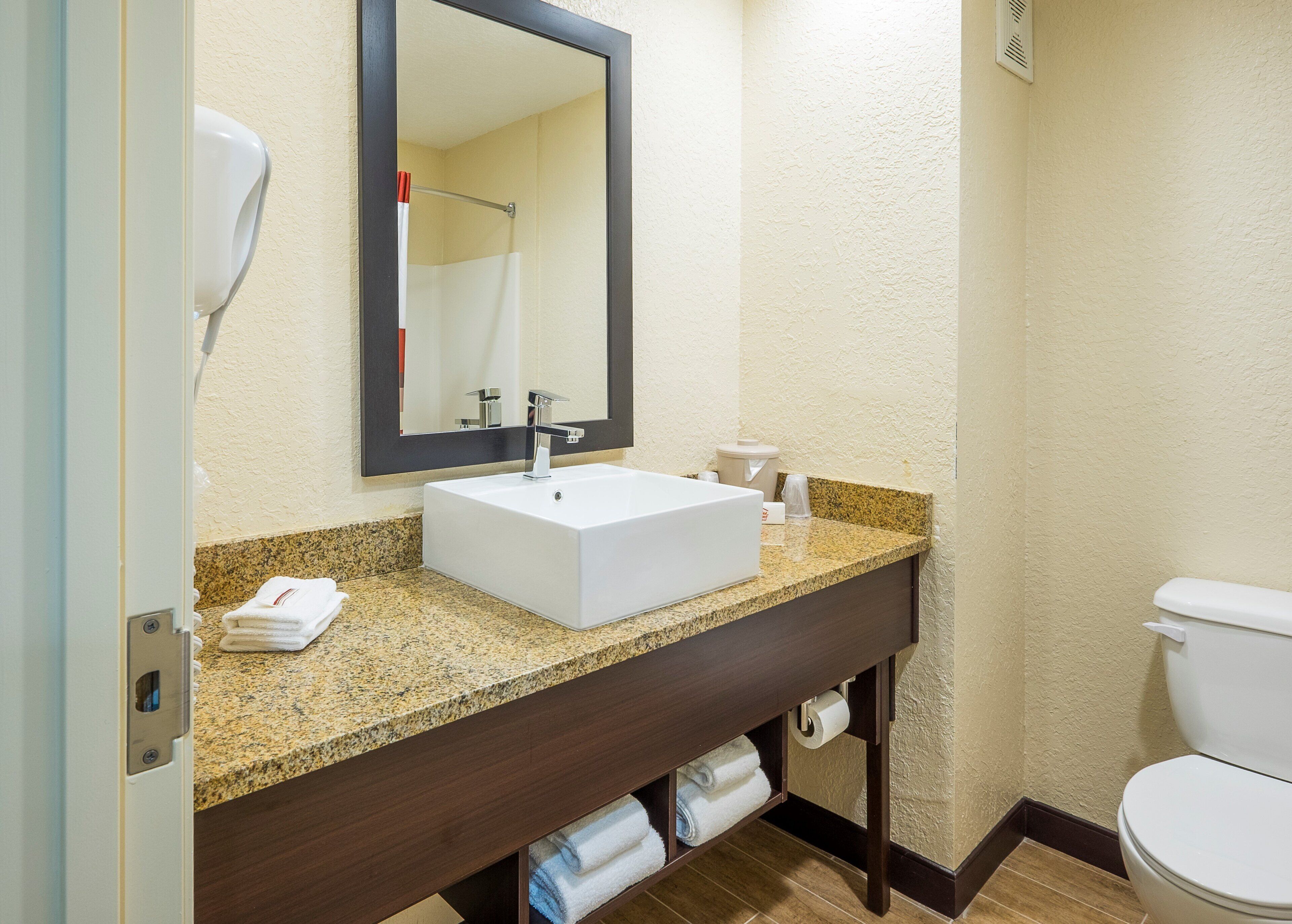 A bathroom with a white sink, dark wooden vanity, and a toilet.