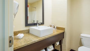 A bathroom with a white sink, dark wooden vanity, and a toilet.