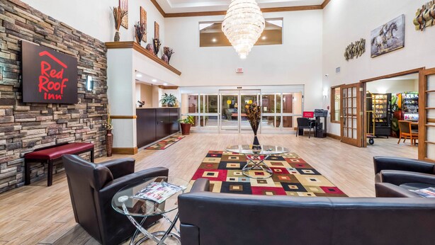 A hotel lobby with a reception desk, seating area, and a chandelier. - Red Roof Inn Ocala (Ocala)