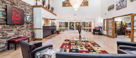 A hotel lobby with a reception desk, seating area, and a chandelier.