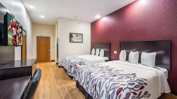 A hotel room with two beds, a desk, a TV, and a painting on the wall.