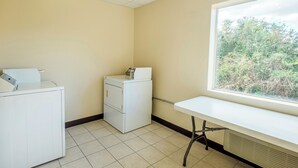 A laundry room with a washing machine, dryer, and a table near a window.