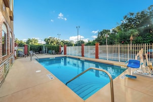 Una piscina con cerca blanca, silla de salvavidas y banco.