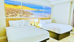 Ein Hotelzimmer mit zwei Betten, einem großen Wandgemälde mit Strandmotiv und Holzboden.