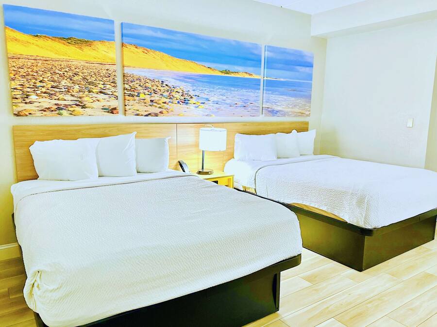 Una camera d'albergo con due letti, un grande affresco raffigurante una spiaggia sulla parete e un pavimento in legno.