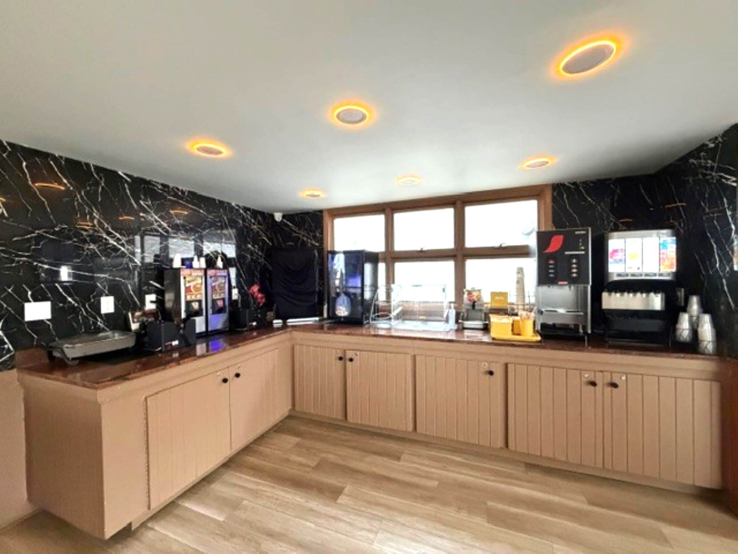 A modern kitchen with marble walls, wooden cabinets, and a large window.