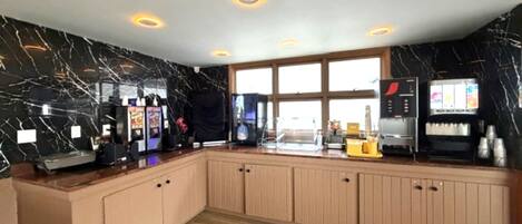 A modern kitchen with marble walls, wooden cabinets, and a large window.