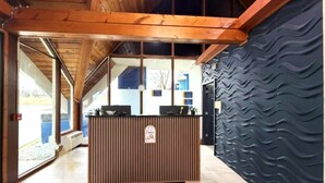Ein Empfangsschalter mit Holzoptik, eine Wand mit schwarzer Struktur und eine blaue Fußmatte mit dem Schriftzug 'Days Inn'.