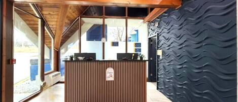 Un mostrador de recepción con detalles de madera, una pared de textura negra y una alfombra azul con el texto 'Days Inn'.