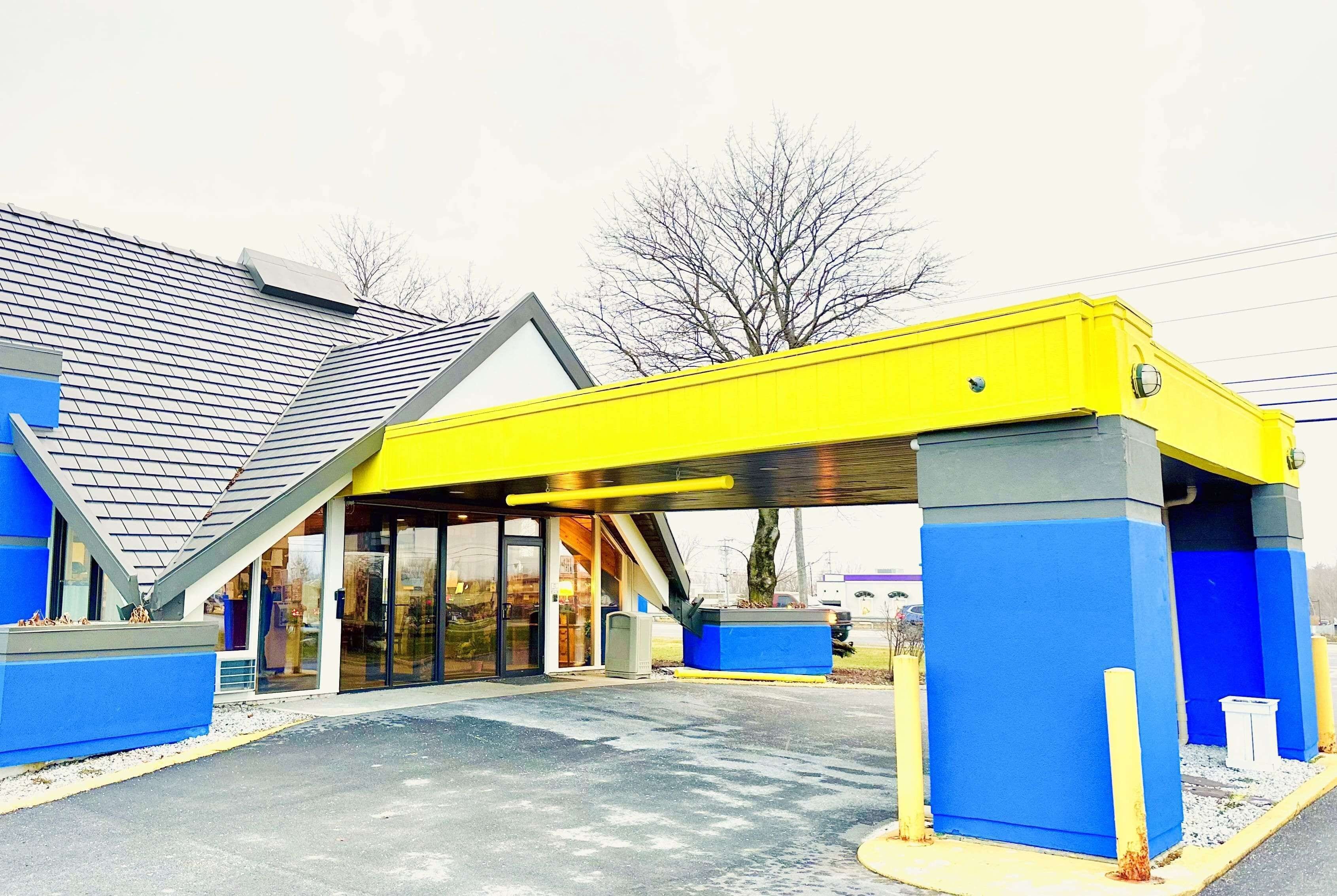 Un edificio con toldo amarillo, paredes azules y entrada de vidrio.