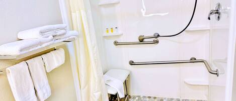 A bathroom with a shower, grab bars, a toilet, and a towel rack.