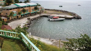 A coastal building with a dock, boats, and a rocky breakwater. - Bird Rock Beach Hotel (Basseterre)