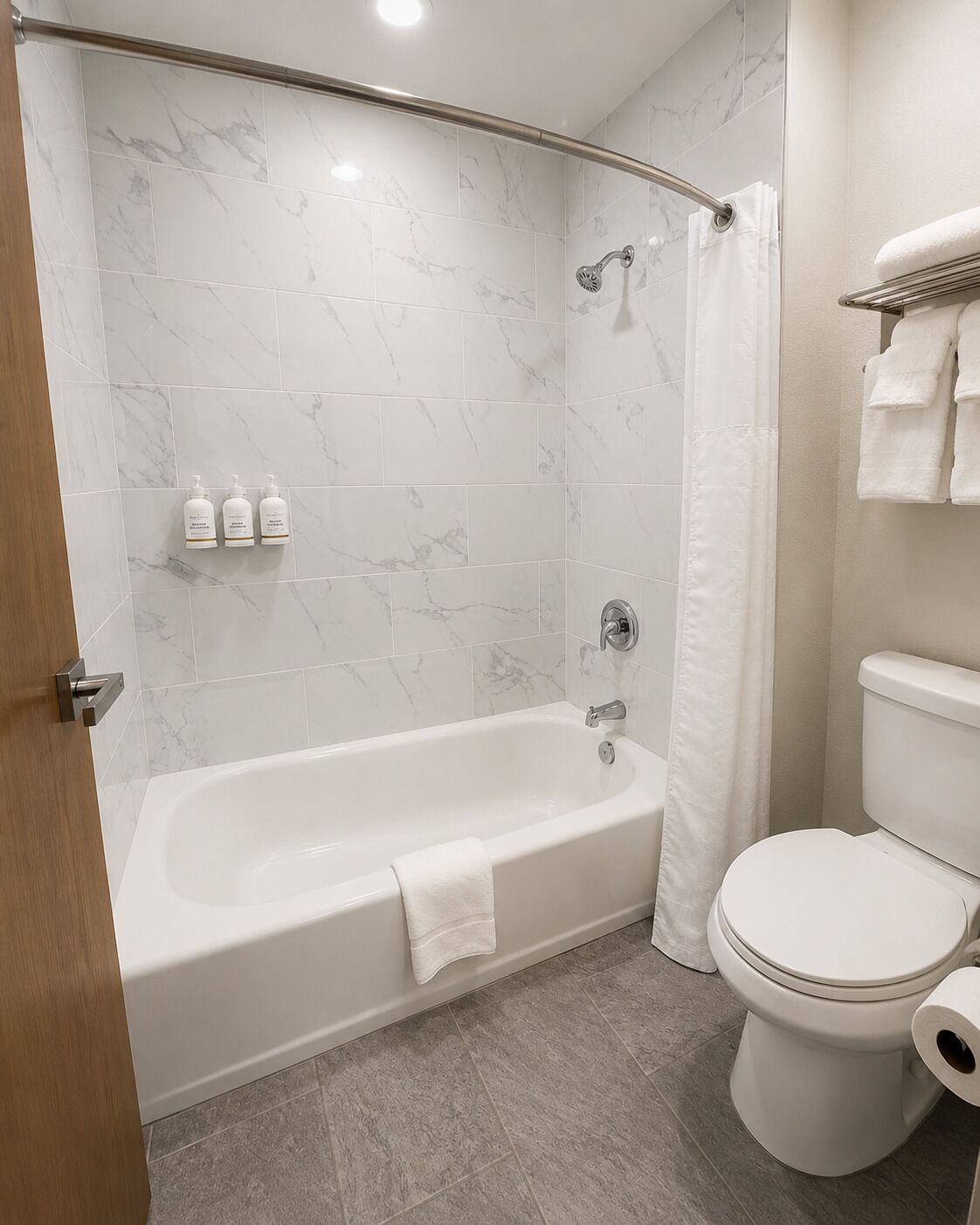 Un baño moderno con bañera, inodoro y baldosas de mármol.