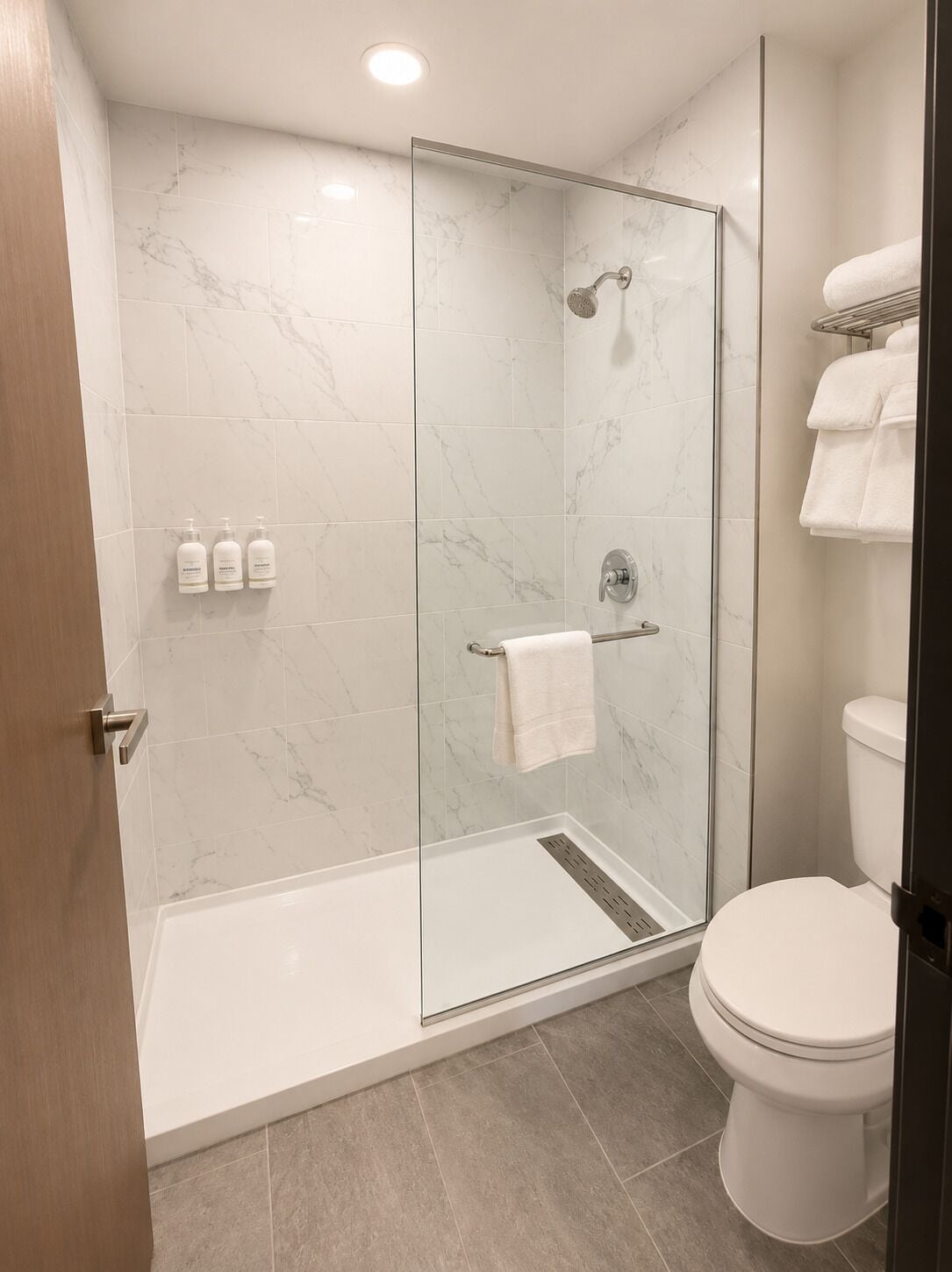 A modern bathroom with a glass-enclosed shower, a toilet, and a towel rack.
