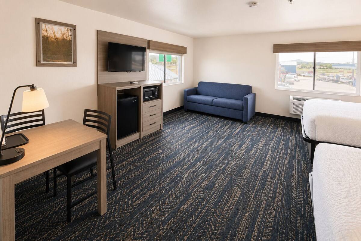 A hotel room with a desk, a television, a sofa, and a bed.