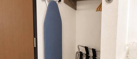 A bathroom with a towel rack, a shower curtain, and a wooden door.