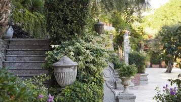 Una escalera de piedra conduce a un jardín con abundante vegetación y macetas grandes.