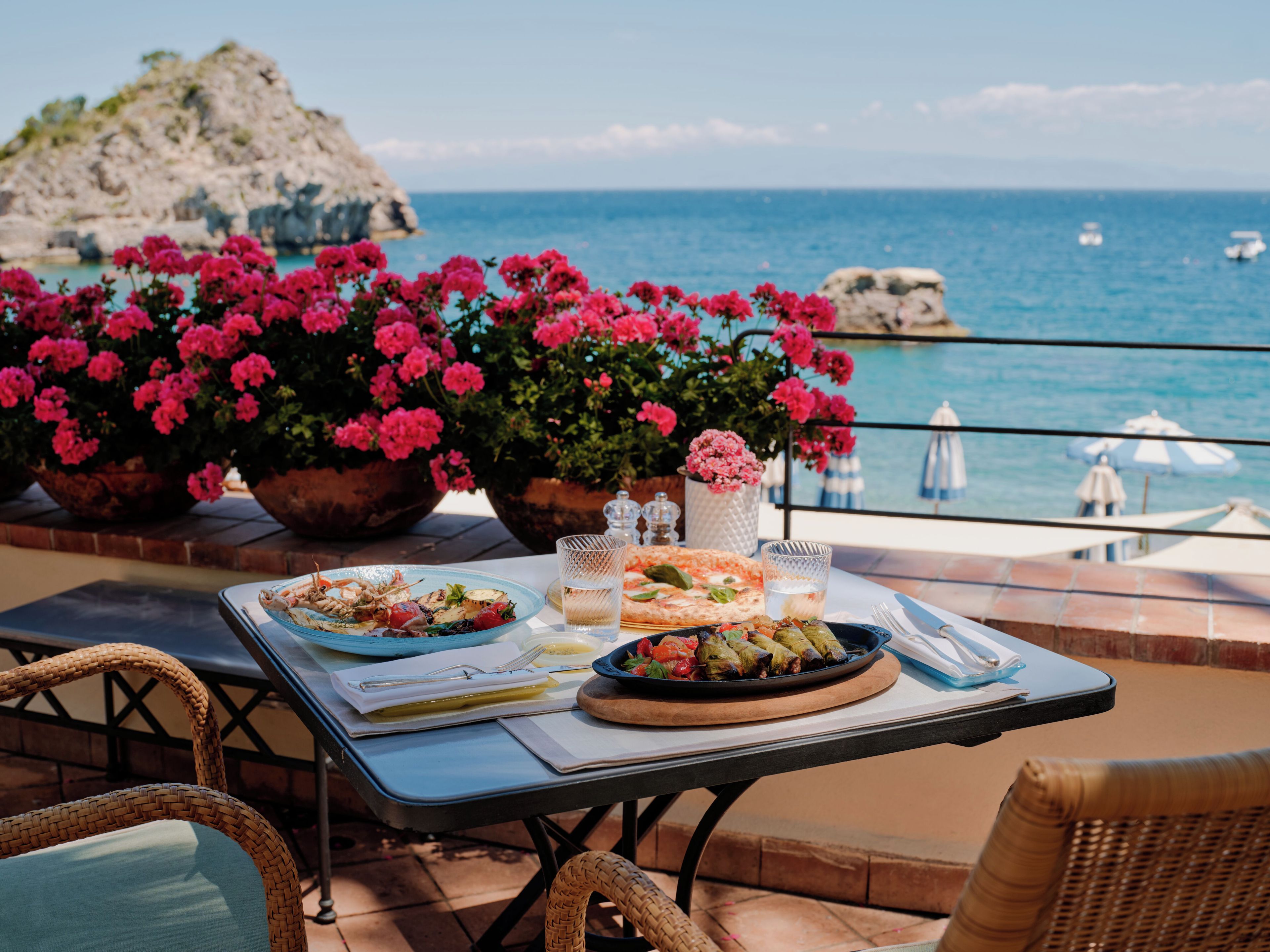 Ein Tisch mit Speisen und Getränken auf einem Balkon mit Blick aufs Meer.