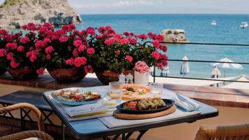 Ein Tisch mit Speisen und Getränken auf einem Balkon mit Blick aufs Meer.