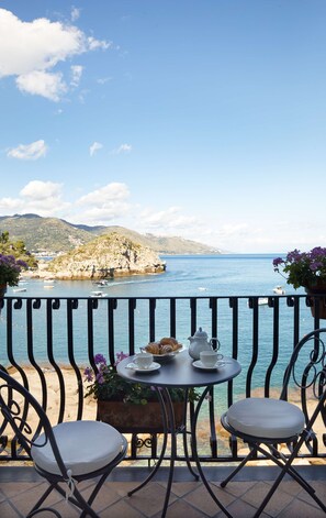 A balcony with a table set for breakfast, overlooking a coastal view with boats and a rocky landscape. - Villa Sant'Andrea, A Belmond Hotel, Taormina Mare (Taormina)