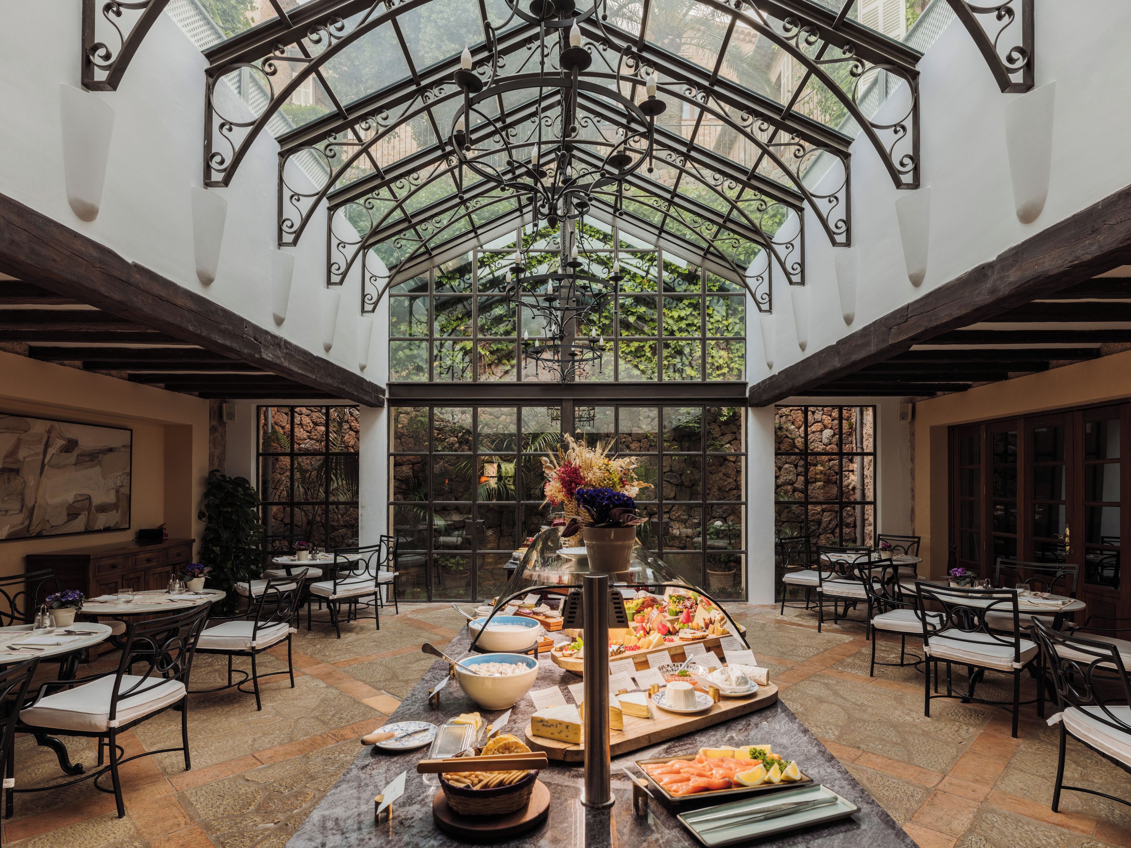 Un vaste espace intérieur doté d’un plafond en verre, de nombreuses tables et d’un buffet central proposant une variété de plats.
