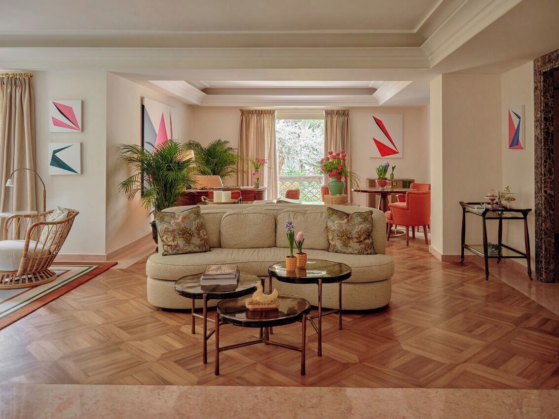Un salon comprenant un canapé, une table basse et des fauteuils, un coin repas avec une table et des chaises, et un balcon agrémenté de plantes.