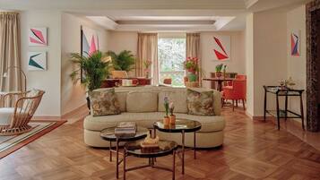 Un salon comprenant un canapé, une table basse et des fauteuils, un coin repas avec une table et des chaises, et un balcon agrémenté de plantes.