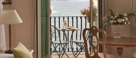 Habitación de hotel con cama, una silla, una mesa, una lámpara y vista al mar.