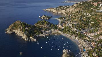 An aerial view of a coastal town with a marina, buildings, and natural landscape.