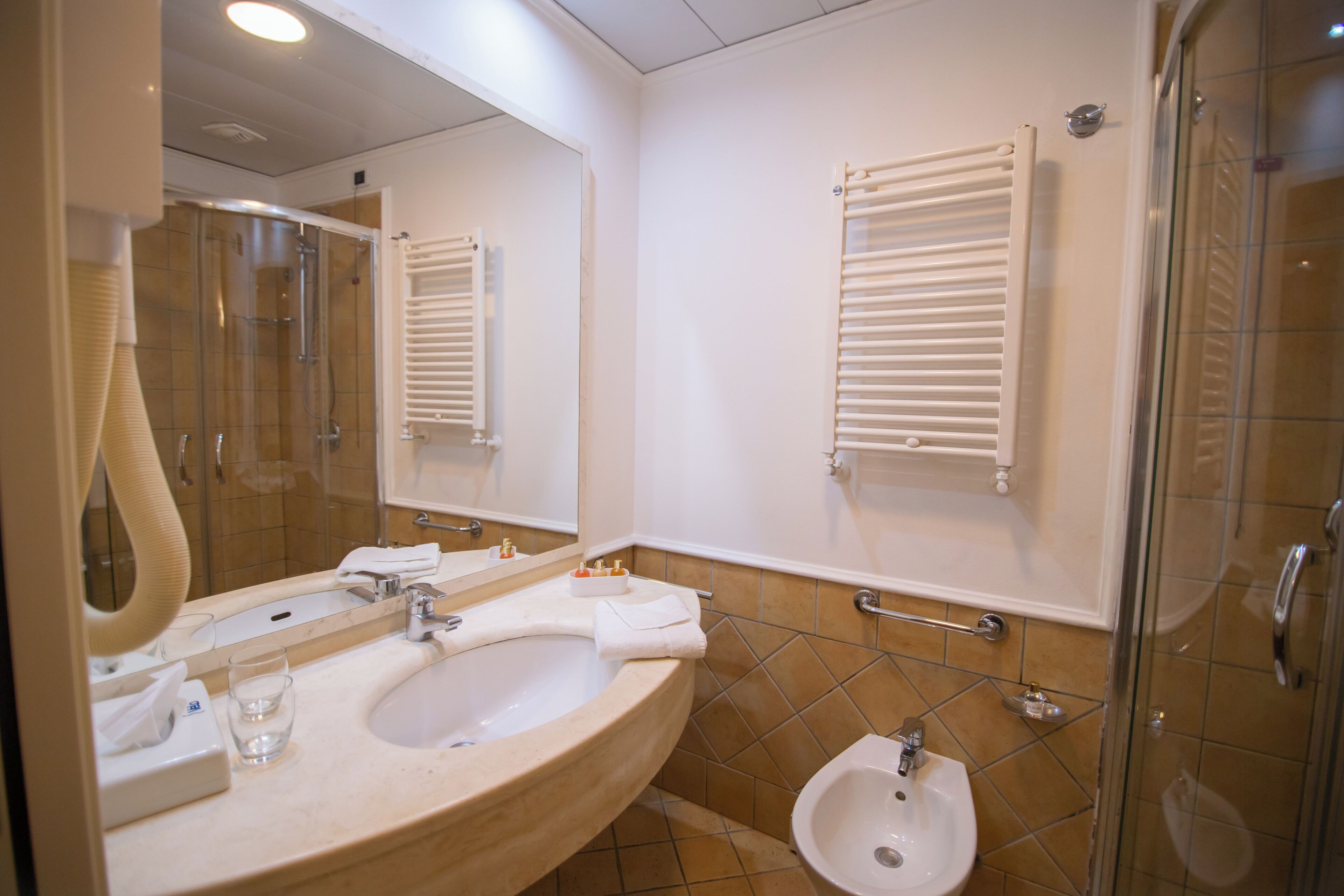 Un bagno con lavandino, bidet, specchio e cabina doccia in vetro.