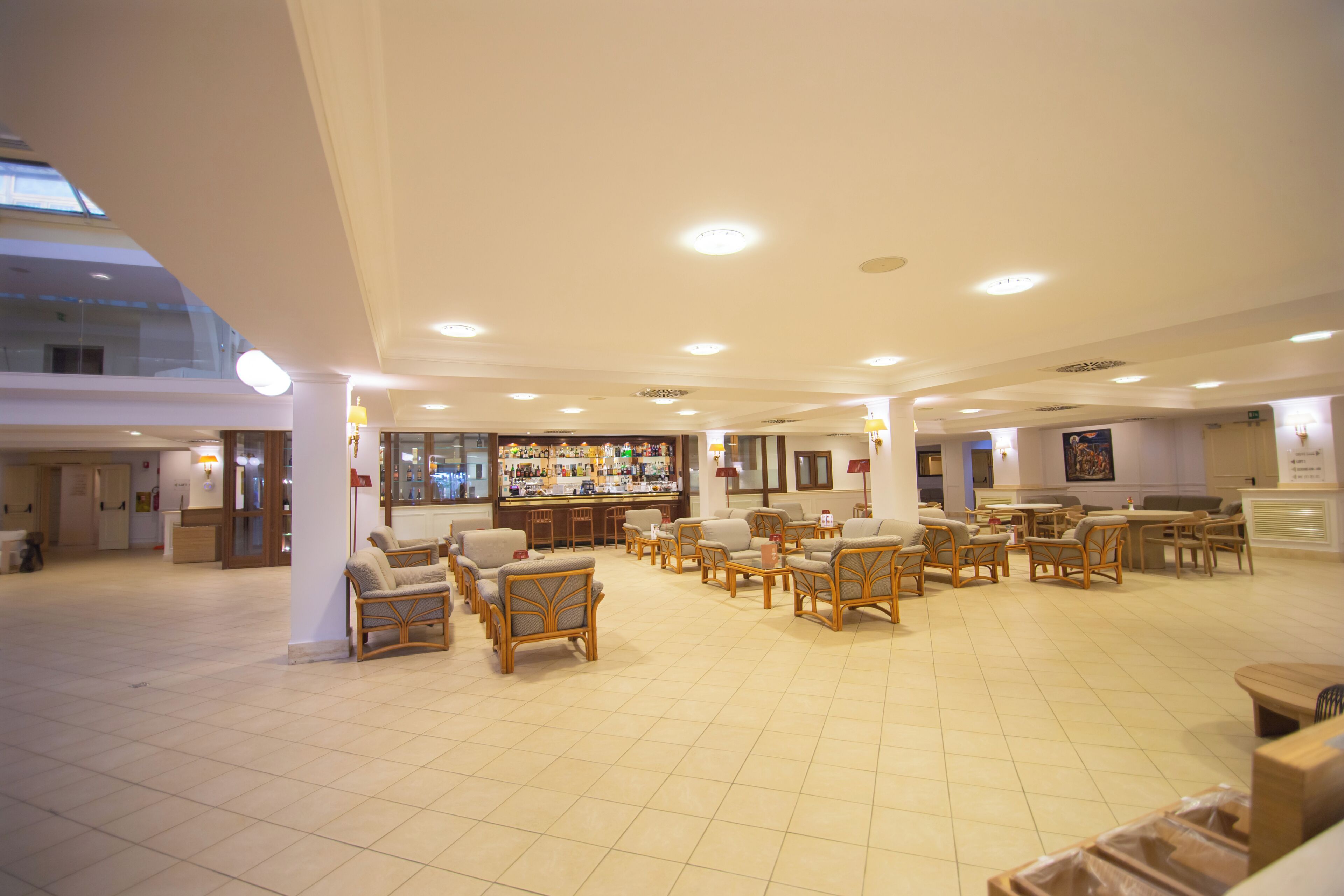 A spacious lobby with multiple seating areas, a bar, and a high ceiling with recessed lighting.