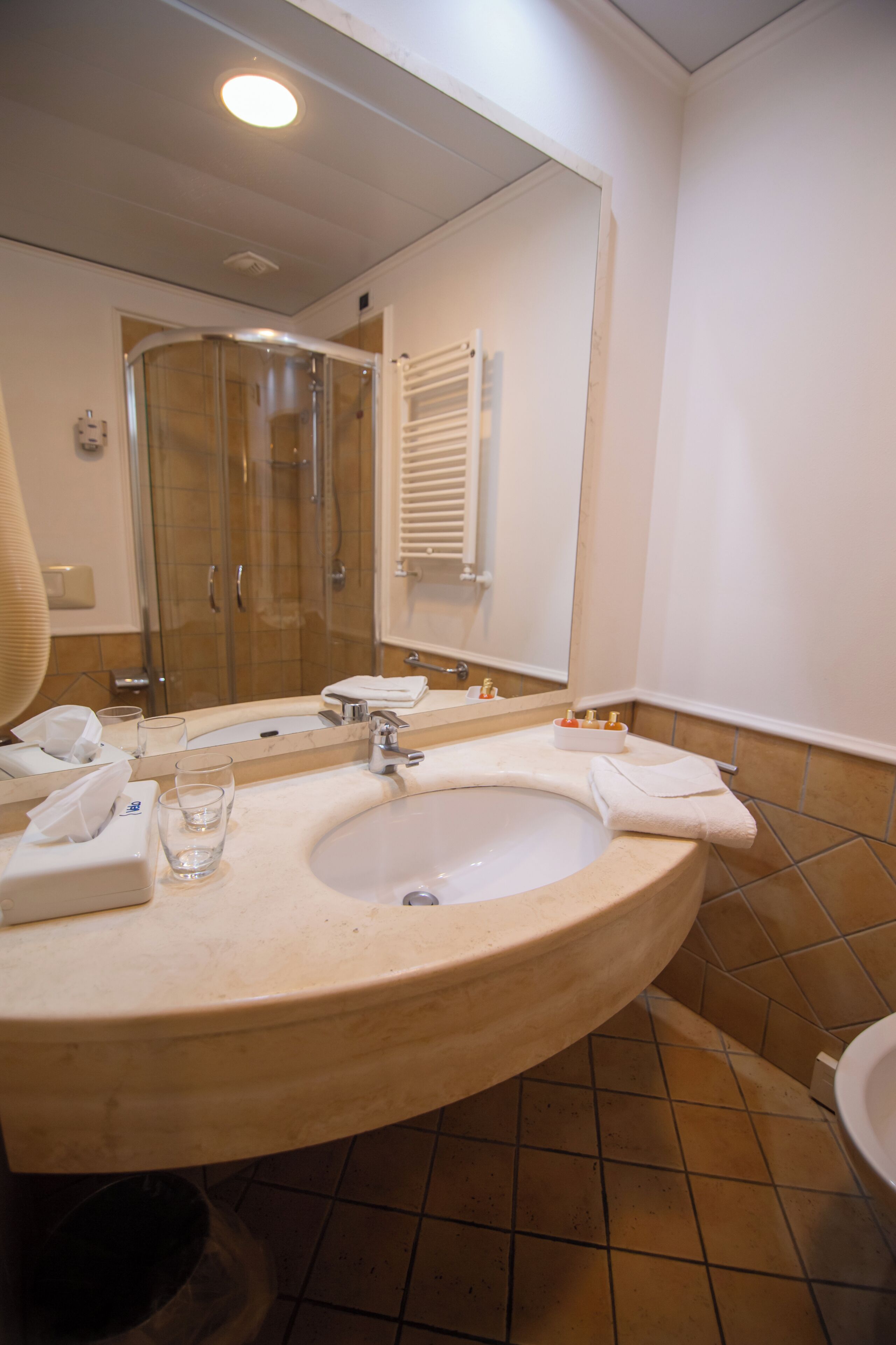 A bathroom with a sink, mirror, glass, towel, and shower.