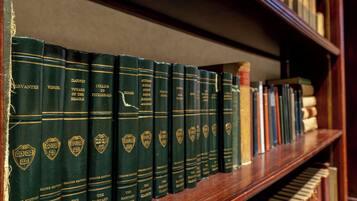 Une bibliothèque remplie de livres à couverture rigide, dont certains avec des titres dorés et d’autres avec des titres noirs.