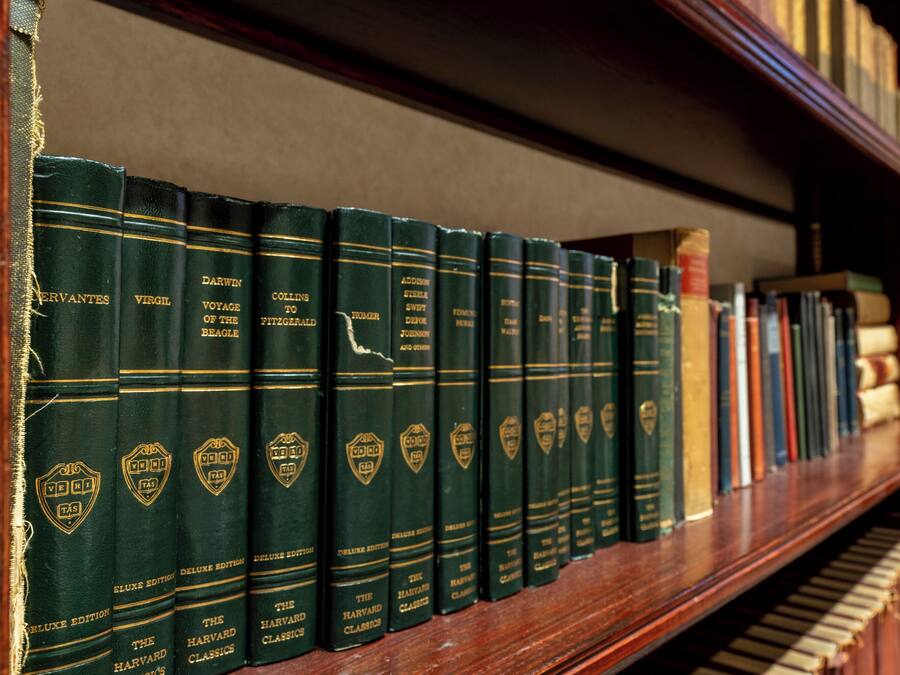 Une bibliothèque remplie de livres à couverture rigide, dont certains avec des titres dorés et d’autres avec des titres noirs.