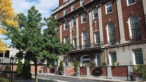 A historic brick building with multiple windows, a central entrance, and a well-maintained lawn. - Inn on Broadway (Rochester)
