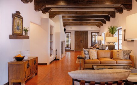 A cozy living room with a leather sofa, wooden cabinet, and a large window with a view.