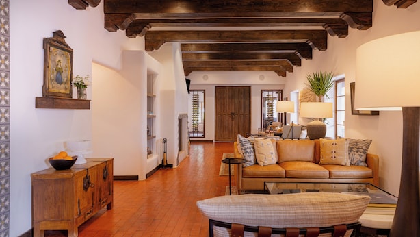A cozy living room with a leather sofa, wooden cabinet, and a large window with a view.