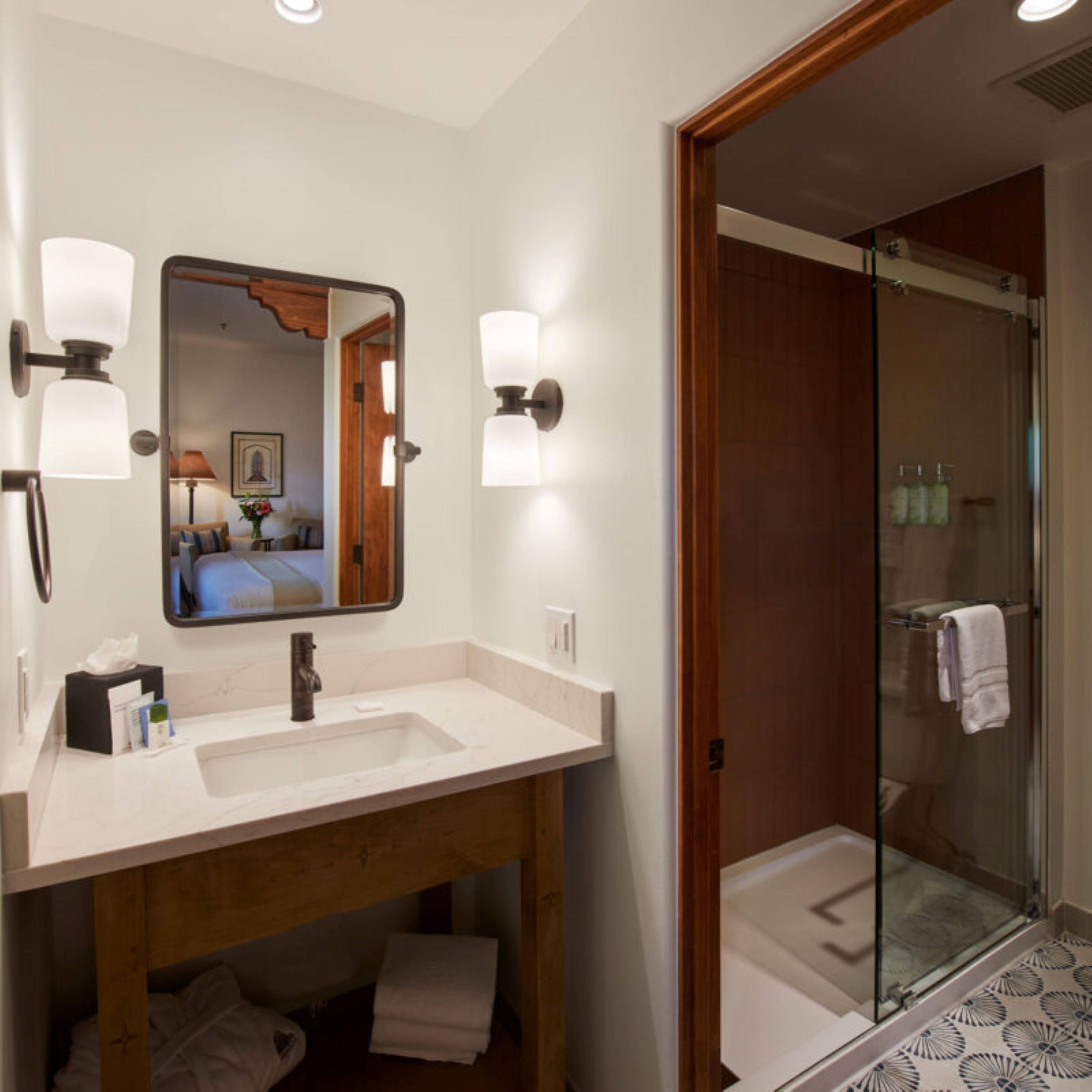 A bathroom with a wooden vanity, a large mirror, and a glass shower enclosure.