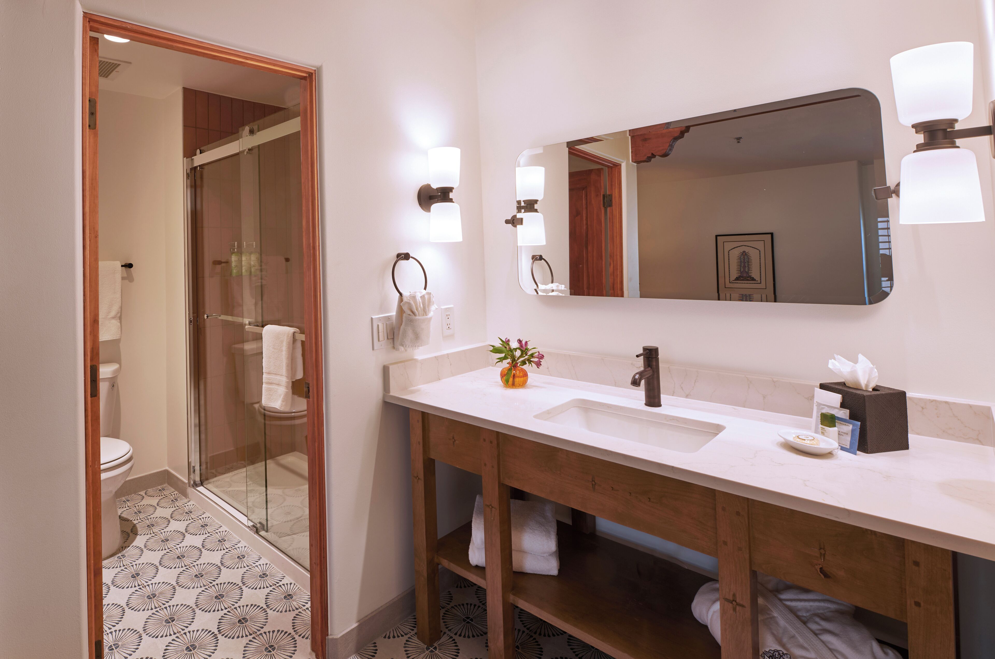 A bathroom with a wooden vanity, a large mirror, and a glass shower enclosure.