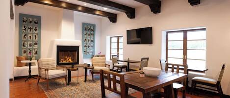 A cozy living room with a fireplace, a dining area, and a large window providing natural light.