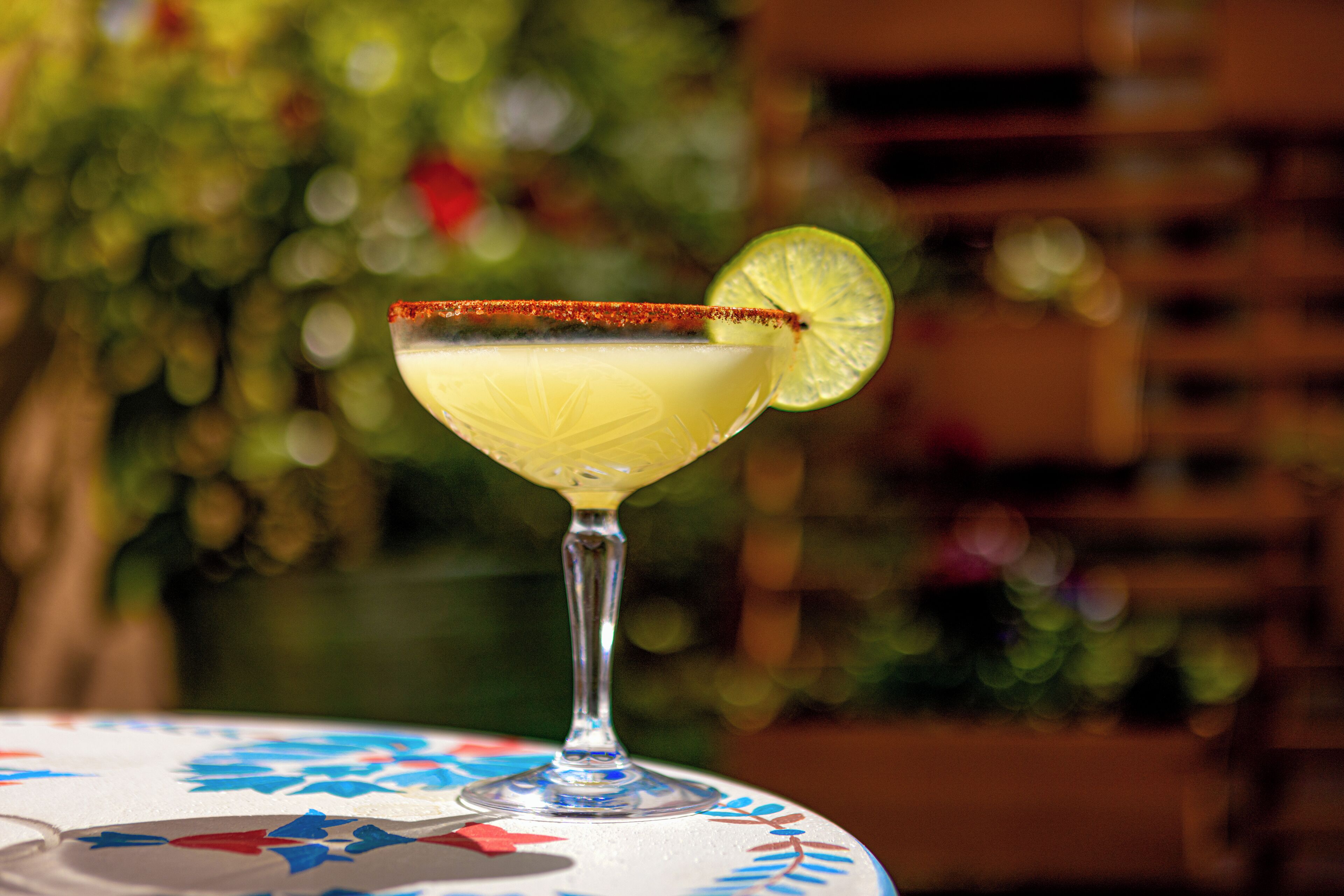 A margarita cocktail on a table with a floral tablecloth.