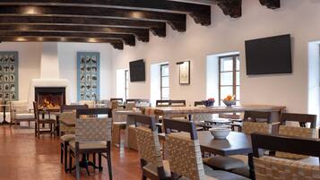 A spacious dining area with high ceilings, exposed beams, and a variety of seating options including bar stools and cushioned chairs.